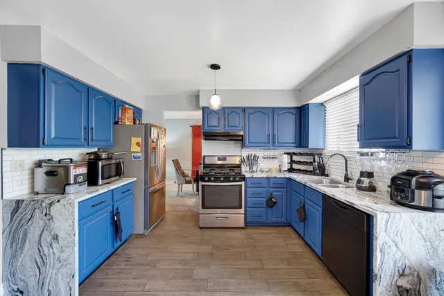 a kitchen with stainless steel appliances granite countertop a stove top oven a sink dishwasher and a refrigerator with wooden cabinets