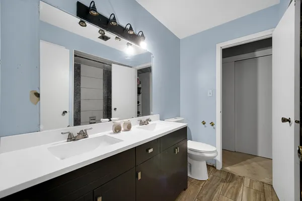 a bathroom with a double vanity sink a toilet and a mirror