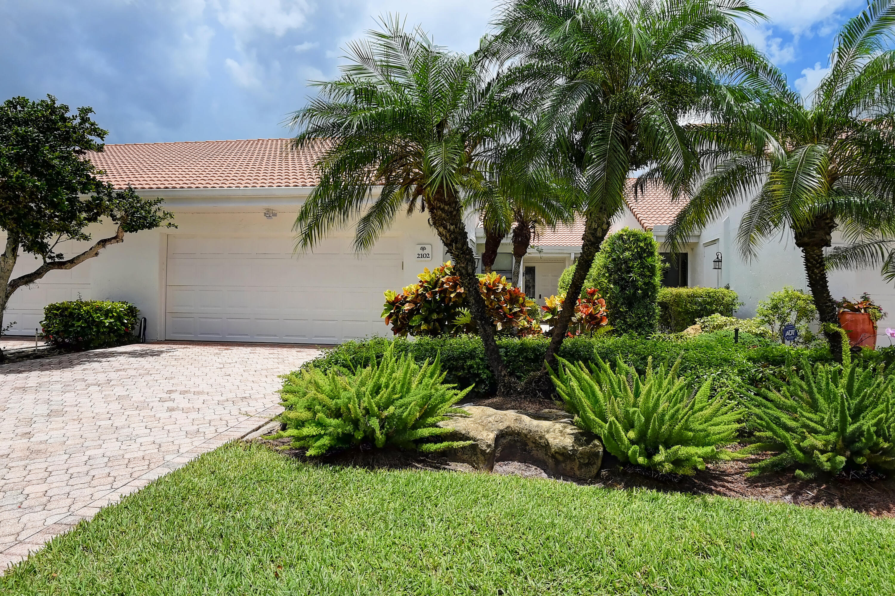 a view of a house with a yard and palm trees