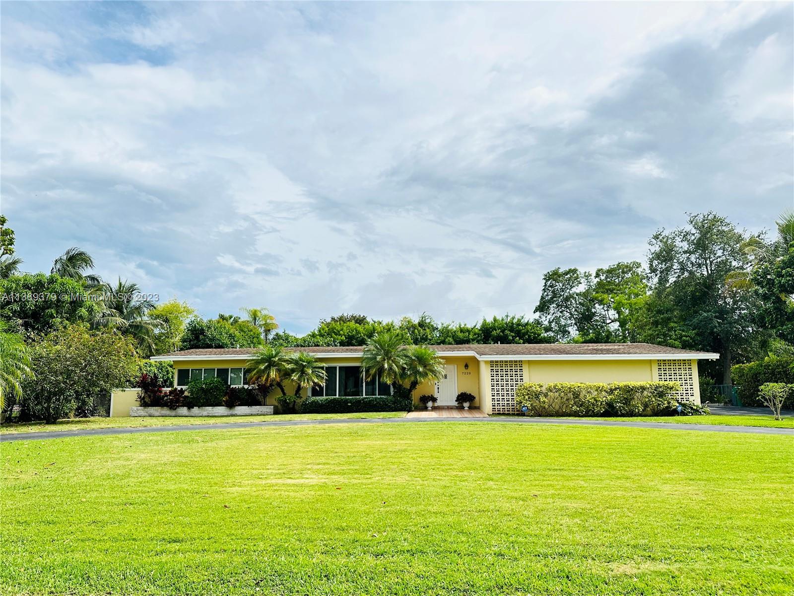 7220 Southwest 125th Street Pinecrest, FL 33156 - Photo 1 of 1 a front view of a building with garden