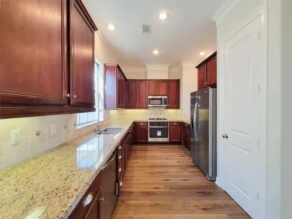 a large kitchen with stainless steel appliances granite countertop a stove a sink and a refrigerator