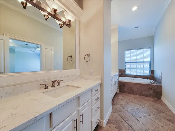 a spacious bathroom with a granite countertop sink a mirror a bathtub and next to a window