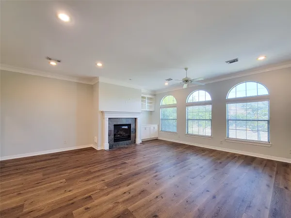 an empty room with wooden floor fireplace and windows