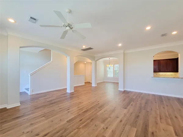 a view of an empty room with wooden floor and a ceiling fan