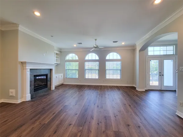 an empty room with wooden floor fireplace and windows