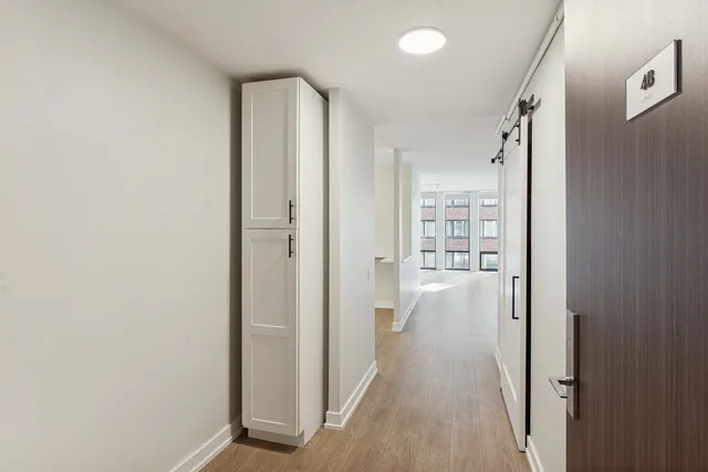 a view of a hallway with wooden floor and a bathroom