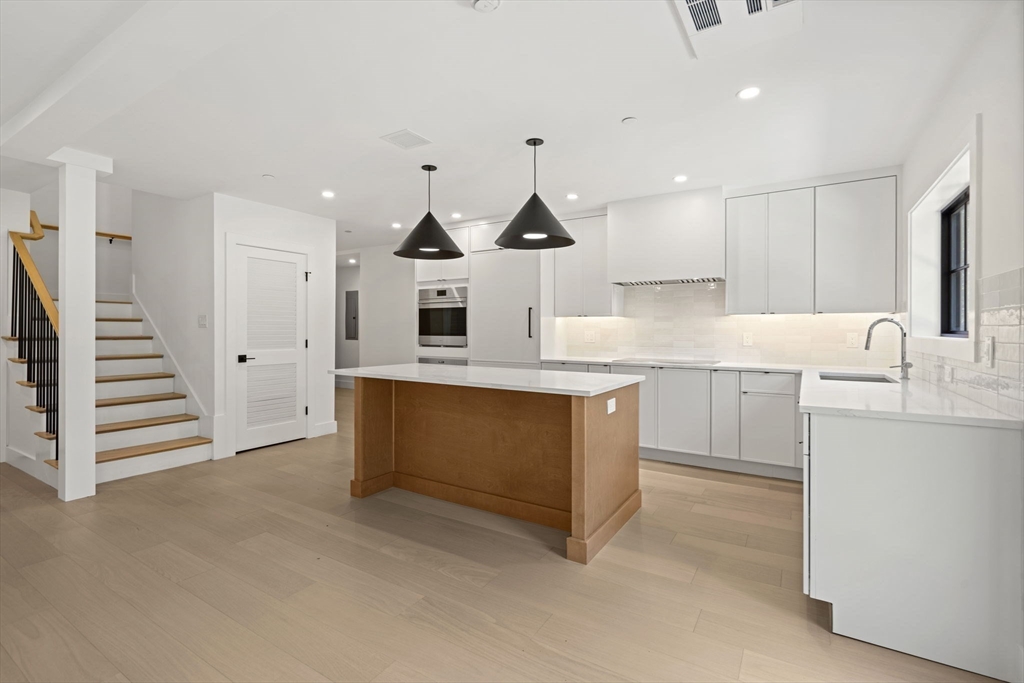 145 Warren Street, Unit 4 Newton, MA 02459 - Photo 6 of 35 a kitchen with stainless steel appliances kitchen island granite countertop a sink a stove and cabinets