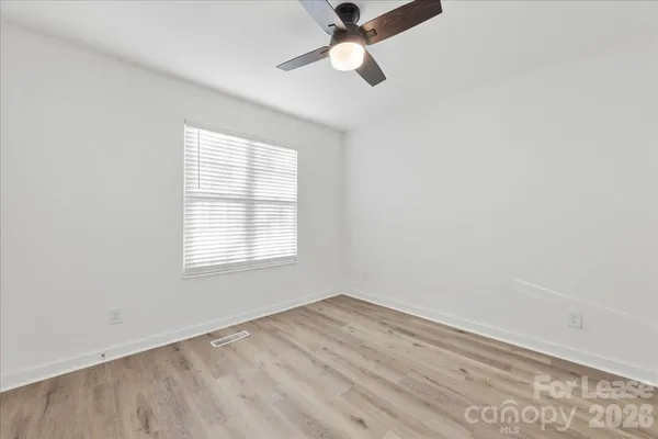 an empty room with a window and a ceiling fan