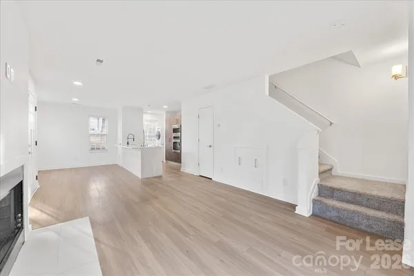 a view of an empty room with wooden floor and stairs