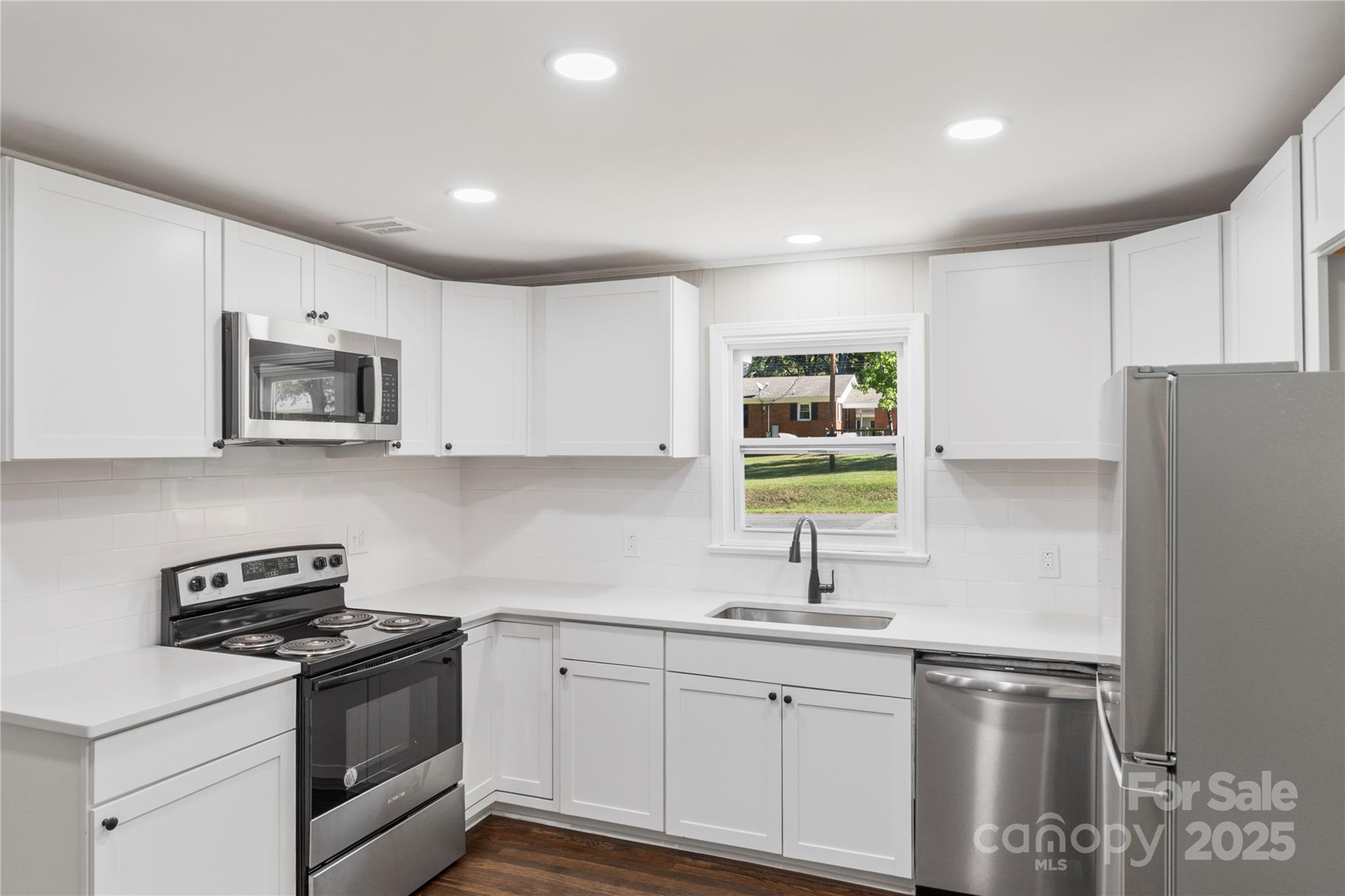 1428 Boxwood Avenue Lancaster, SC 29720 - Photo 19 of 44 a kitchen with stainless steel appliances granite countertop a sink a stove a microwave a refrigerator a stove and white cabinets