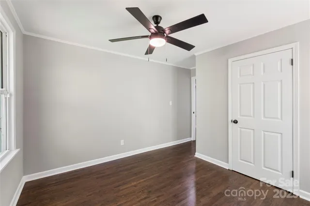an empty room with wooden floor ceiling fan and windows