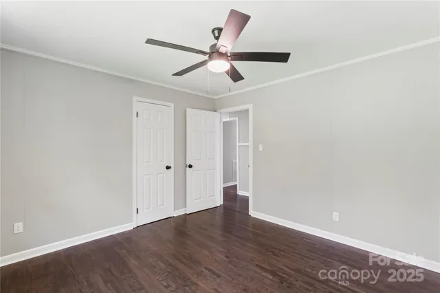 an empty room with wooden floor ceiling fan and windows