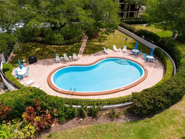 an aerial view of a swimming pool with a yard and outdoor seating