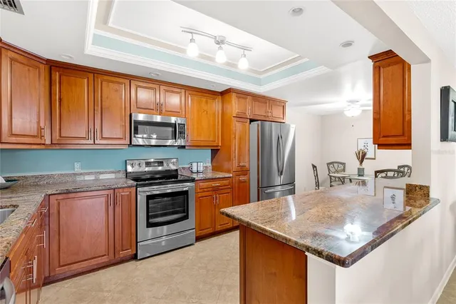 a kitchen with stainless steel appliances granite countertop a sink stove microwave refrigerator and cabinets