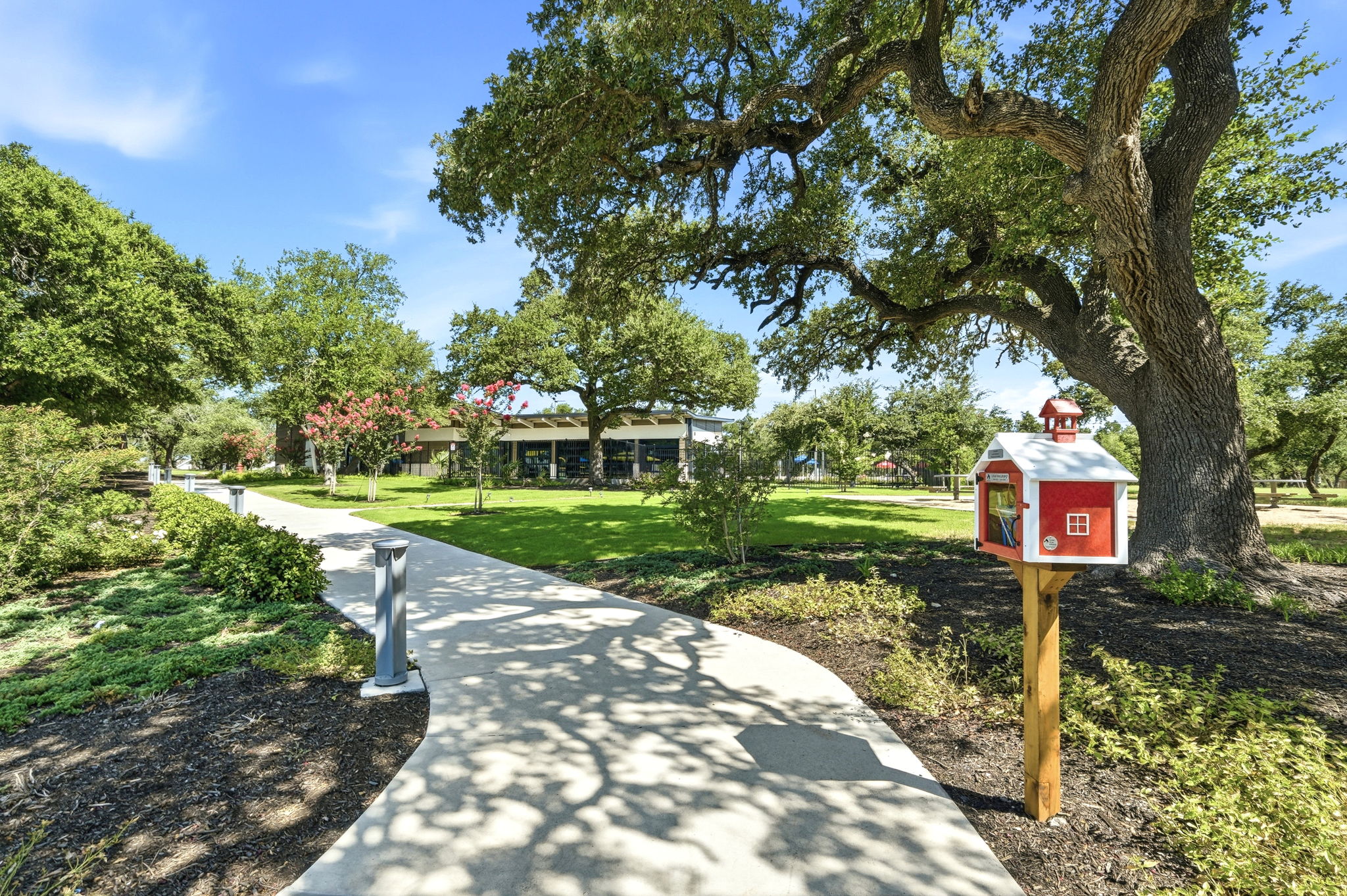 220 Lucky Texan Road Jarrell, TX 76537 - Photo 16 of 19 Meandering pathway through a verdant park, shaded by mature trees, leading to a charming community library.