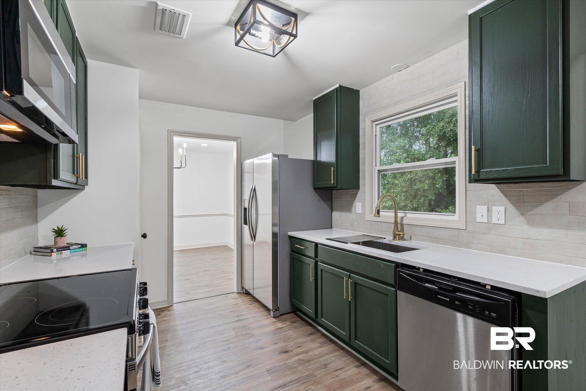 3655 Claridge Road South Mobile, AL 36608 - Photo 11 of 32 Kitchen featuring green cabinets, stainless steel appliances, decorative backsplash, and light wood finished floors