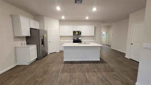 a view of kitchen with microwave a stove and white cabinets