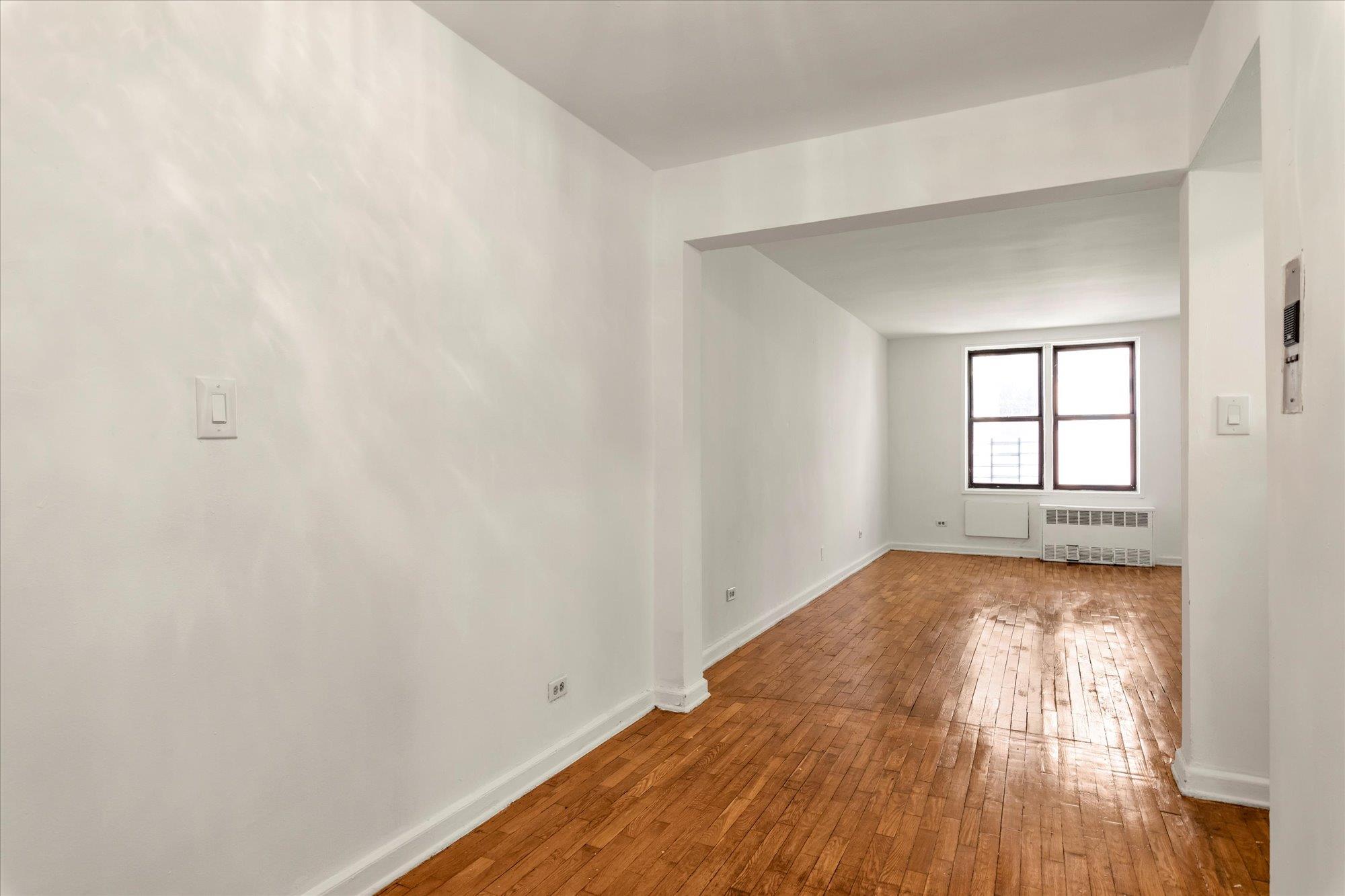 141-05 Pershing Crescent, Unit 117 Queens, NY 11435 - Photo 3 of 16 an empty room with wooden floor and windows