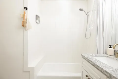a bathroom with a granite countertop sink a mirror and a shower