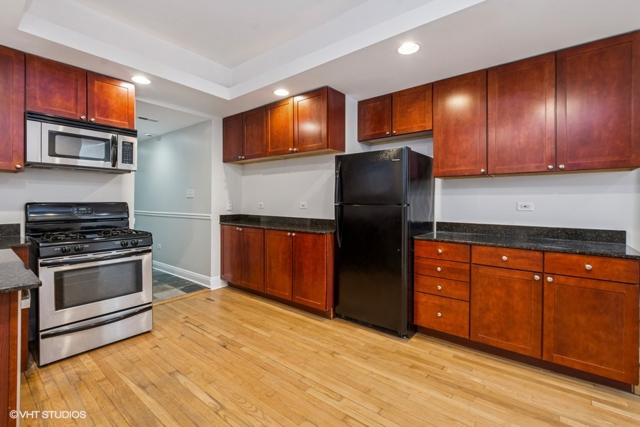 4909 North Janssen Avenue, Unit GDN Chicago, IL 60640 - Photo 4 of 8 a kitchen with stainless steel appliances granite countertop wooden cabinets a stove a sink and a refrigerator