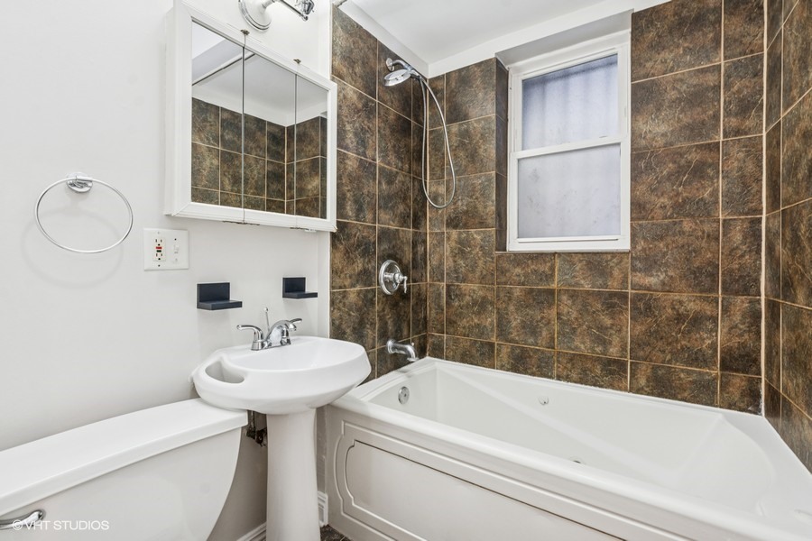 4909 North Janssen Avenue, Unit GDN Chicago, IL 60640 - Photo 7 of 8 a bathroom with a sink a toilet and shower