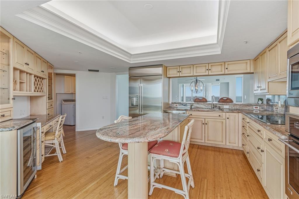 60 Seagate Drive, Unit 1606 Naples, FL 34103 - Photo 7 of 44 a kitchen with stainless steel appliances granite countertop a table chairs stove a sink and dishwasher