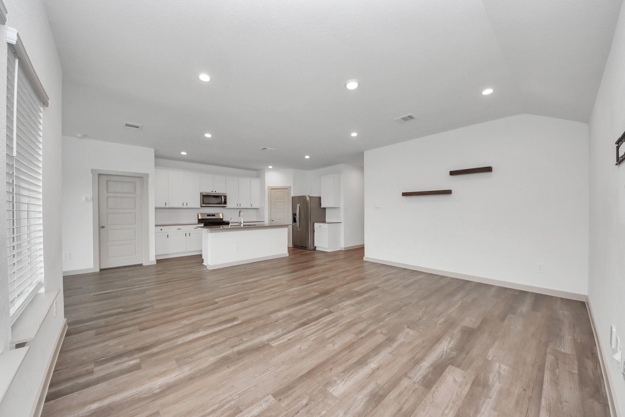 7911 Wrangler Shack Lane Rosharon, TX 77583 - Photo 24 of 40 Spacious open-concept living area with sleek hardwood floors, recessed lighting, and a modern kitchen featuring stainless steel appliances and a large island.