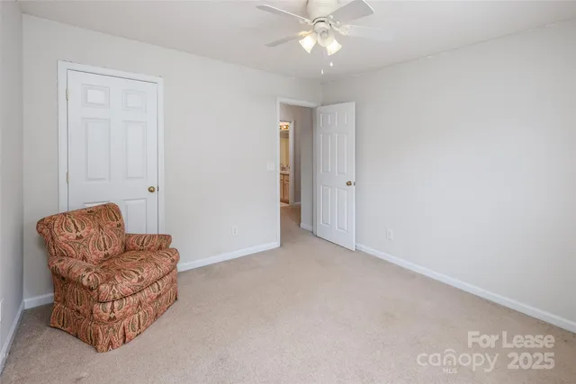an empty room with furniture and a chandelier fan
