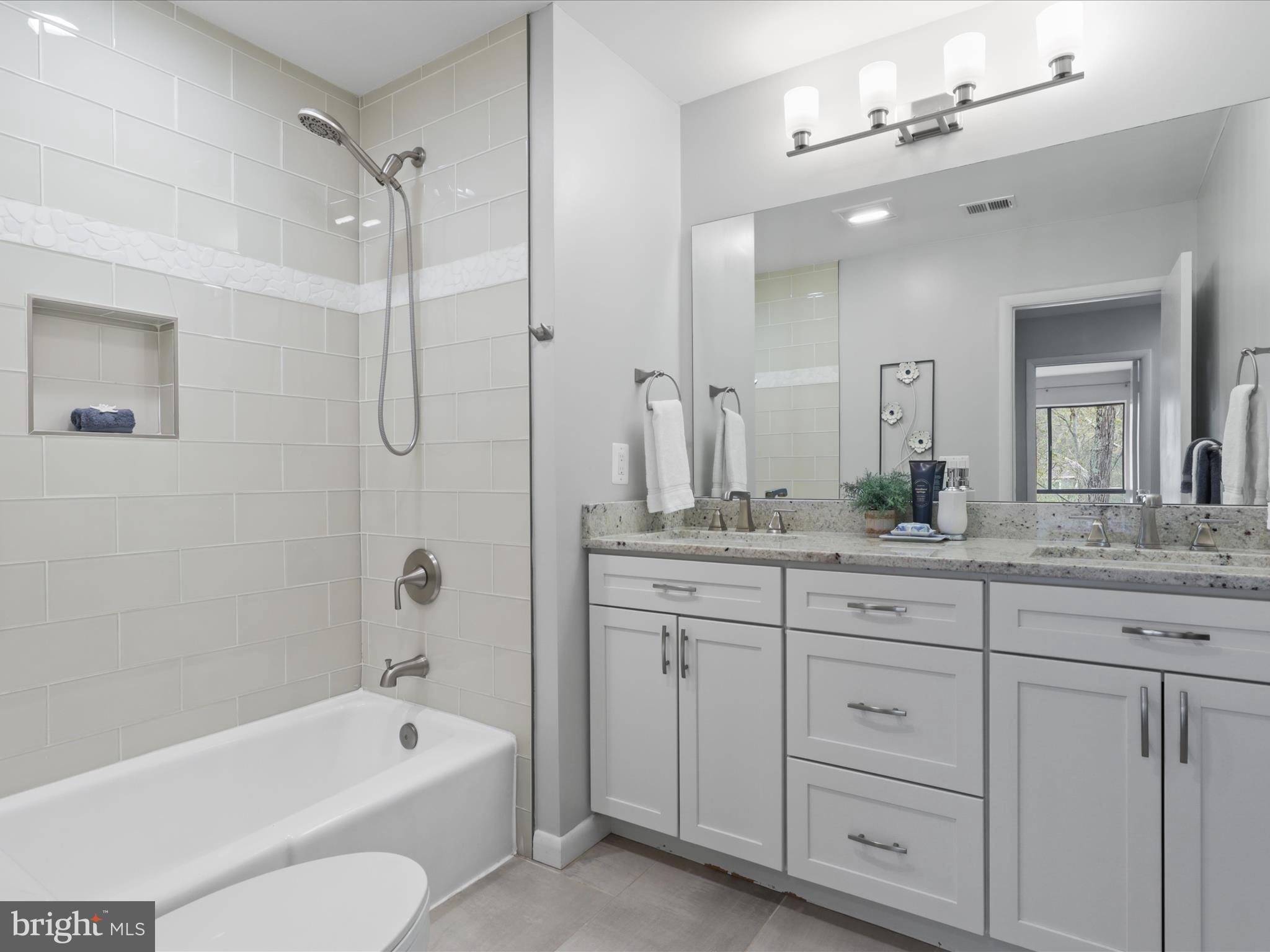 11159 Saffold Way Reston, VA 20190 - Photo 16 of 51 a bathroom with a granite countertop sink a toilet a mirror a bathtub and shower