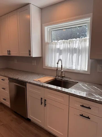 a kitchen with granite countertop white cabinets and white appliances