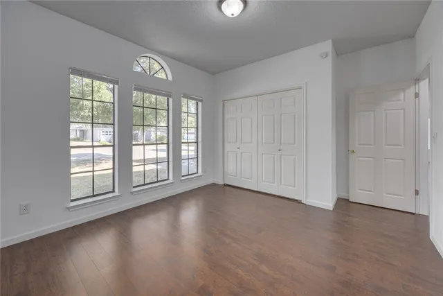 an empty room with wooden floor and windows