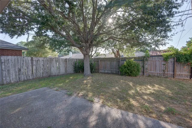 a view of a backyard with large trees and wooden fence