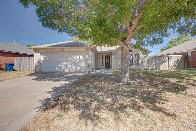 a front view of a house with large trees and a small yard