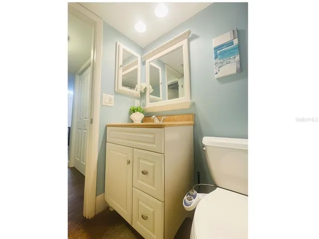 a bathroom with a granite countertop toilet sink and mirror