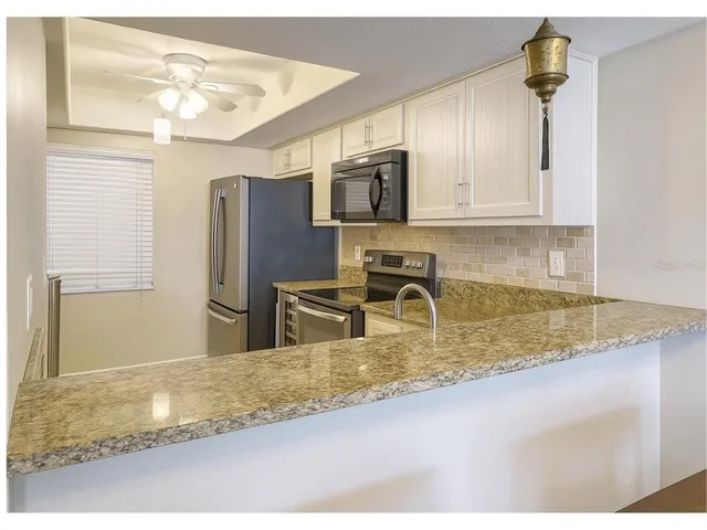 a kitchen with stainless steel appliances granite countertop a sink refrigerator and microwave