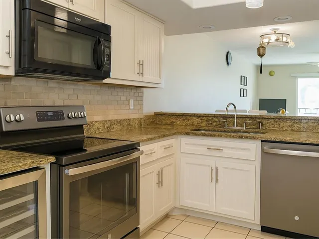 a kitchen with granite countertop white cabinets stainless steel appliances and a sink