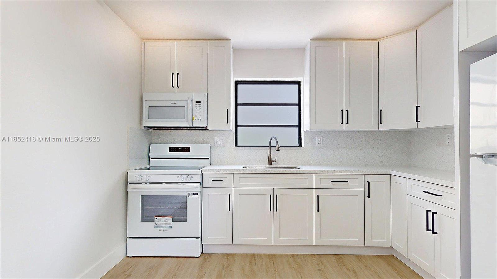 1674 West 42nd Street, Unit 1674 Hialeah, FL 33012 - Photo 12 of 29 a kitchen with white cabinets and white appliances