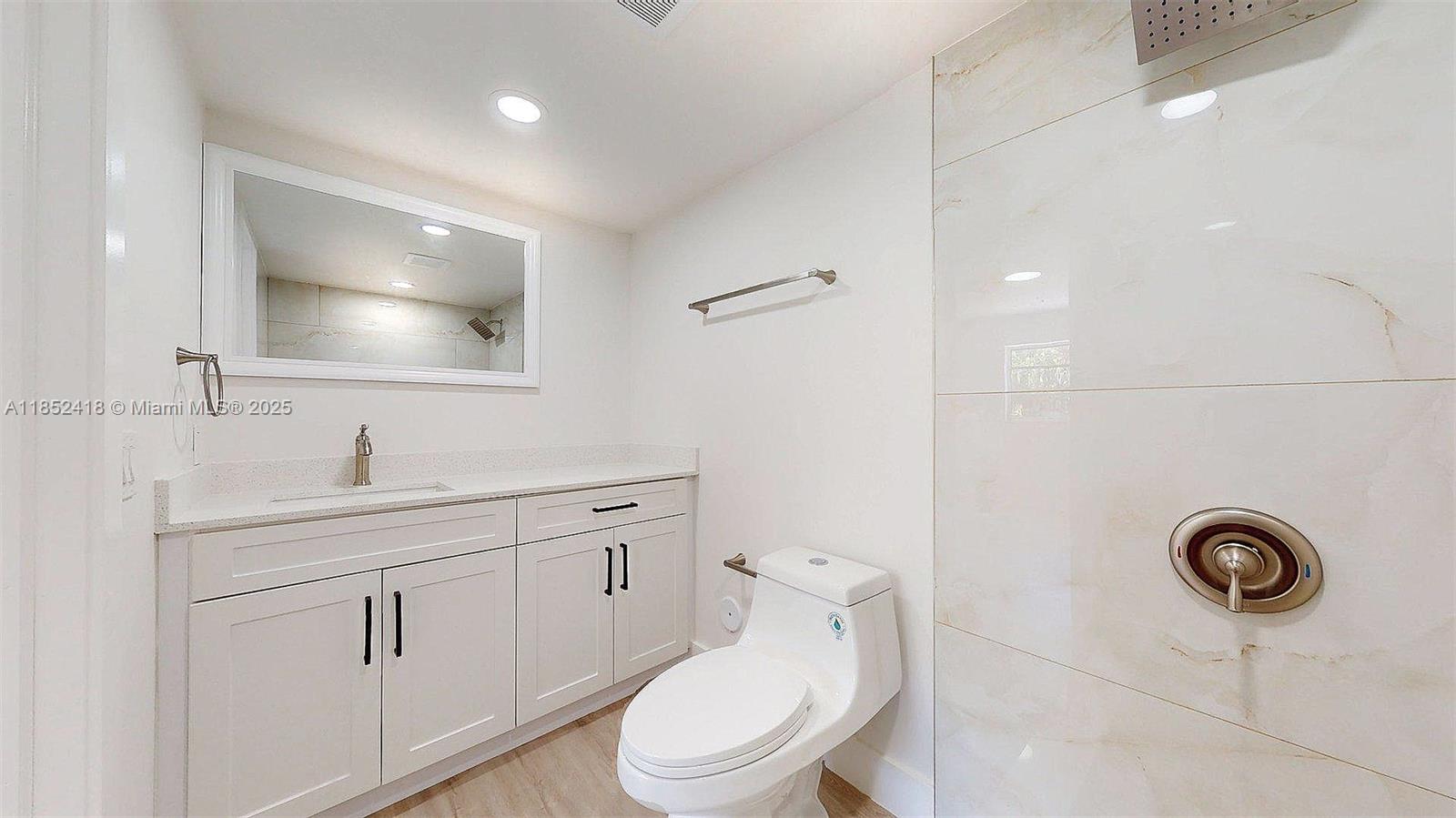 1674 West 42nd Street, Unit 1674 Hialeah, FL 33012 - Photo 24 of 29 a bathroom with a toilet a sink a mirror and vanity