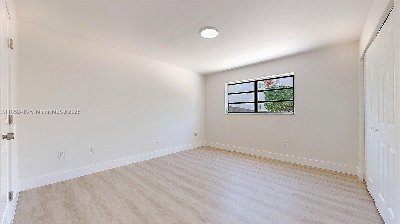 1674 West 42nd Street, Unit 1674 Hialeah, FL 33012 - Photo 25 of 29 an empty room with wooden floor and windows