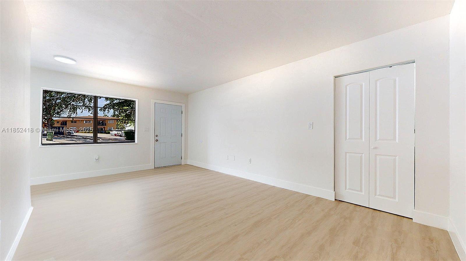 1674 West 42nd Street, Unit 1674 Hialeah, FL 33012 - Photo 7 of 29 an empty room with wooden floor and windows