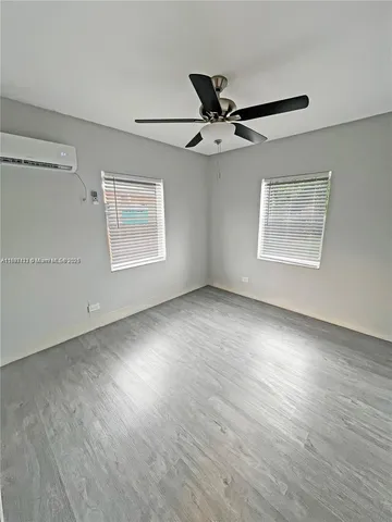 an empty room with wooden floor fan and windows