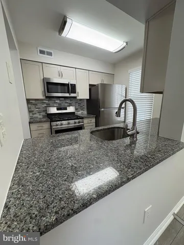 a kitchen with granite countertop a sink and a stove top oven