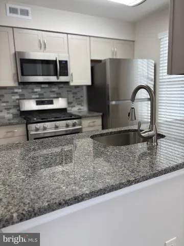 a kitchen with stainless steel appliances granite countertop a sink a stove and a microwave
