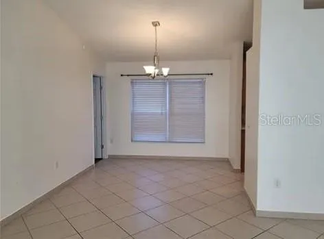 an empty room that has a dining table and chandelier
