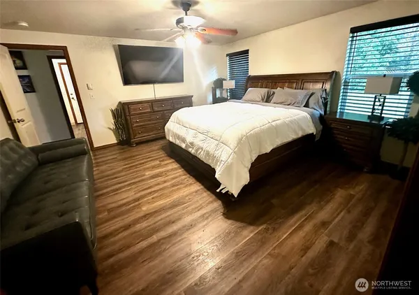 a bedroom with a bed a mirror on dresser and a flat screen tv