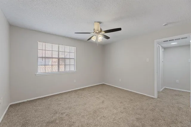 an empty room with windows and fan