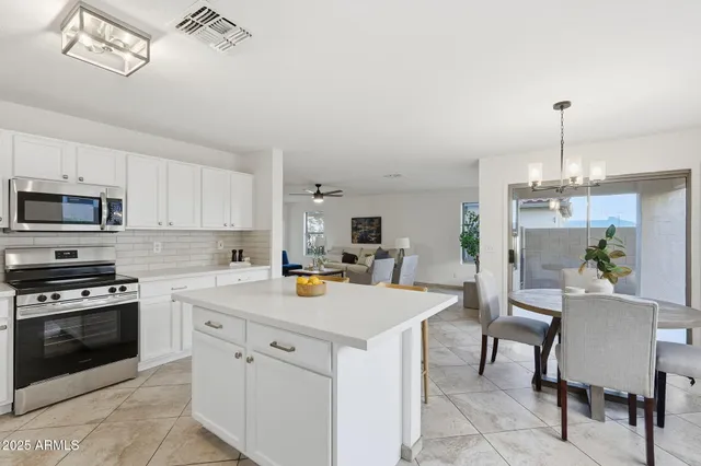 a kitchen with a stove a sink dishwasher a dining table and chairs with wooden floor