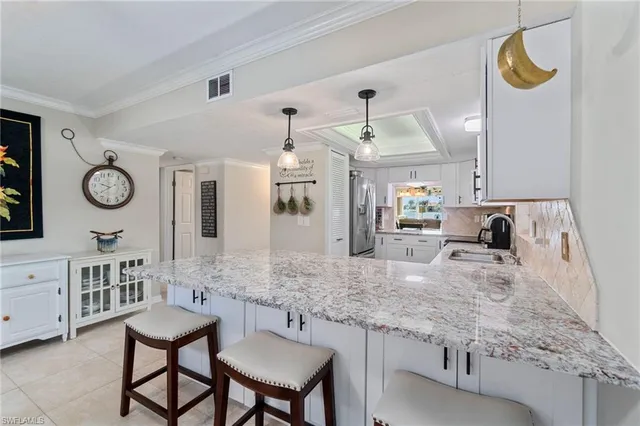 a kitchen with granite countertop a sink stainless steel appliances and white cabinets