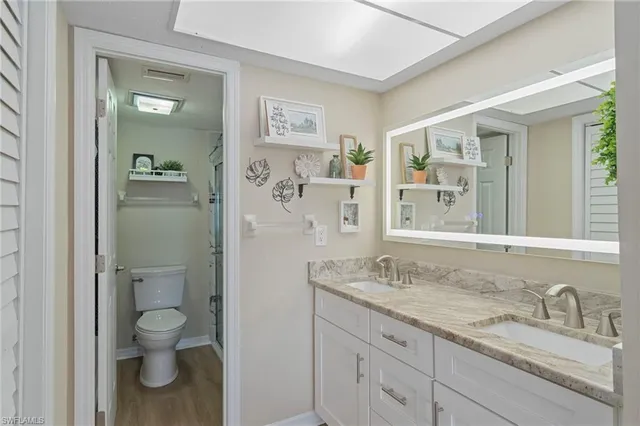 a bathroom with a granite countertop toilet a sink and a mirror