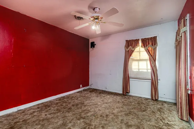 an empty room with a window and a chandelier fan